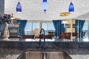 Eine moderne Küche mit Granit-Arbeitsplatten, einer Edelstahl-Spüle und einem Essbereich mit Tisch und Stühlen.