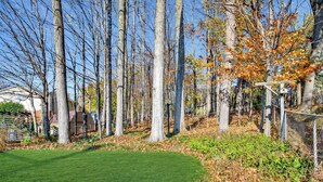 A well-maintained lawn with tall trees and a wooden fence. - Elegant 4BR Home | Private Backyard & Trail Access (Waterloo)