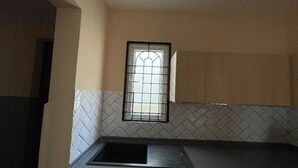A kitchen with a herringbone tile backsplash, a window with a metal grid, and a black countertop.