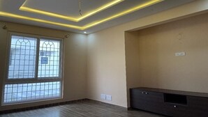A room with a large window, recessed ceiling lighting, and a dark-colored entertainment unit.