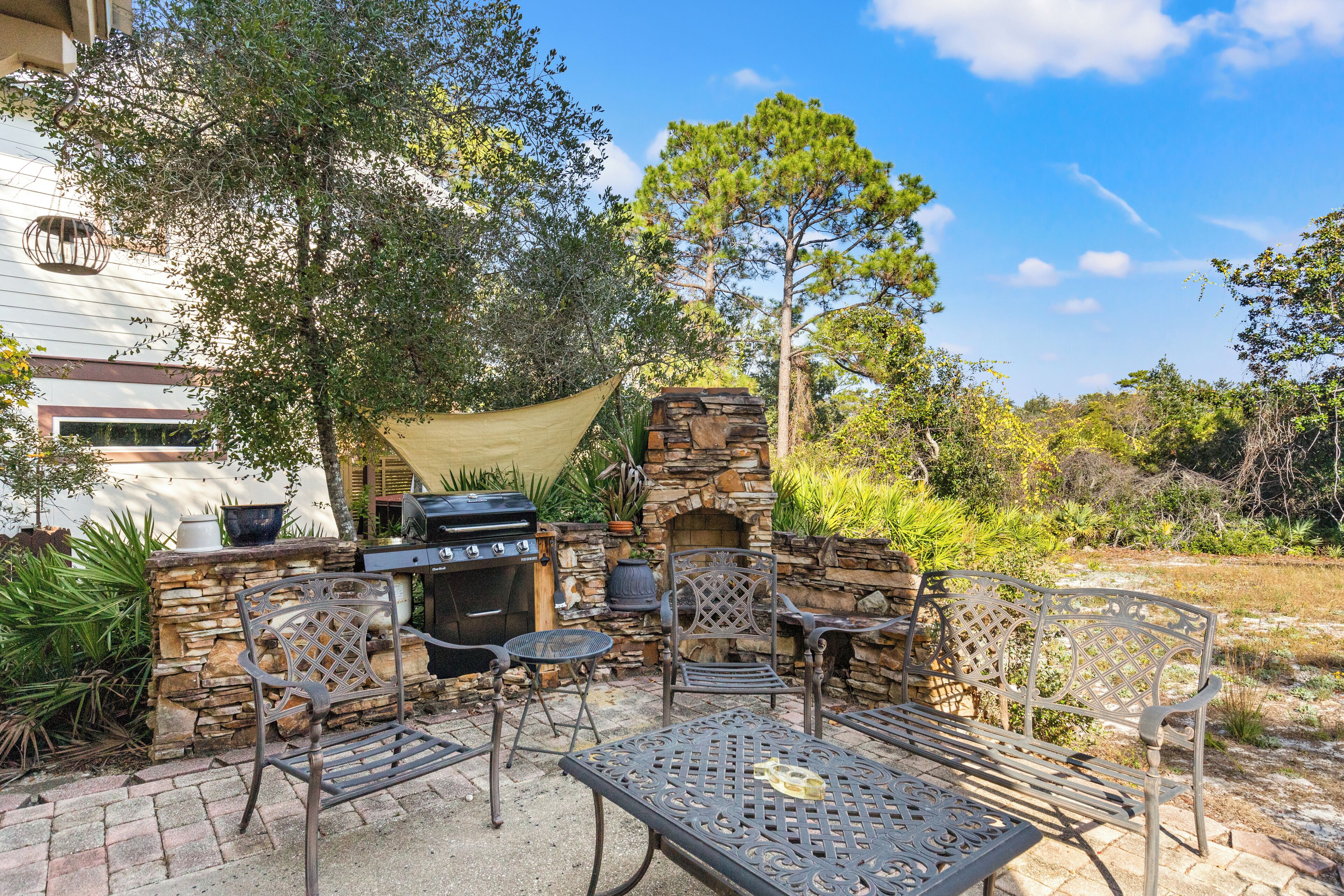 Une terrasse extérieure avec des murs en pierre, un barbecue et du mobilier en métal.