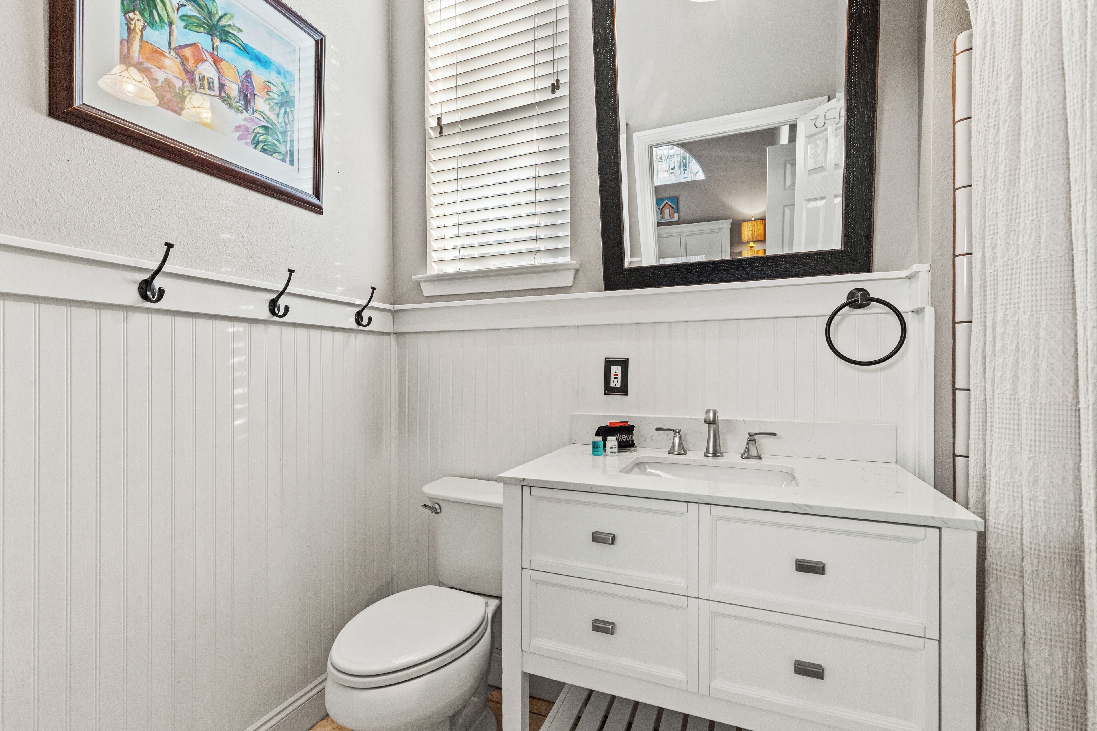 A bathroom with a white vanity, a toilet, a mirror, and a towel rack.