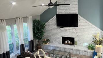 Een moderne woonkamer met een open haard, een bank, een salontafel en een aan de muur bevestigde televisie.