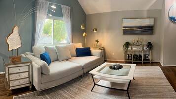 A modern living room with a sofa, a glass coffee table, and a side table.