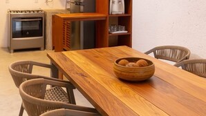 A kitchen with a wooden table, wicker chairs, a hanging light fixture, and a refrigerator. - MHV Milagres - Casa da Villa 08, Casa em Villa (Passo de Camaragibe)