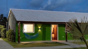 A single-story house with a corrugated metal roof, a hammock hanging on the front porch, and a green exterior wall. - MHV Milagres - Casa da Villa 08, Casa em Villa (Passo de Camaragibe)