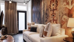 A living room with a beige sofa, a round wooden table, and a patterned wall. - Romantic Designer Loft | Walk to Butler St! (Pittsburgh)