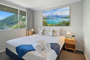 A hotel room with a large bed, a view of mountains and a lake, and a painting of the same view on the wall. - Unmatched Views Newly Renovated Minutes From Town (Queenstown)