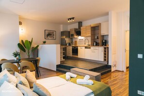 A modern apartment with a dining area, a kitchenette, and a bedroom with a bed and towels. - RR | Modern Living Apartments 1 | 84 m² | Kitchen | Parking (Magdeburg)
