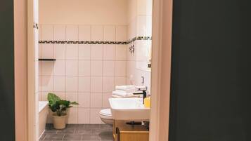 A bathroom with a toilet, sink, and a potted plant.