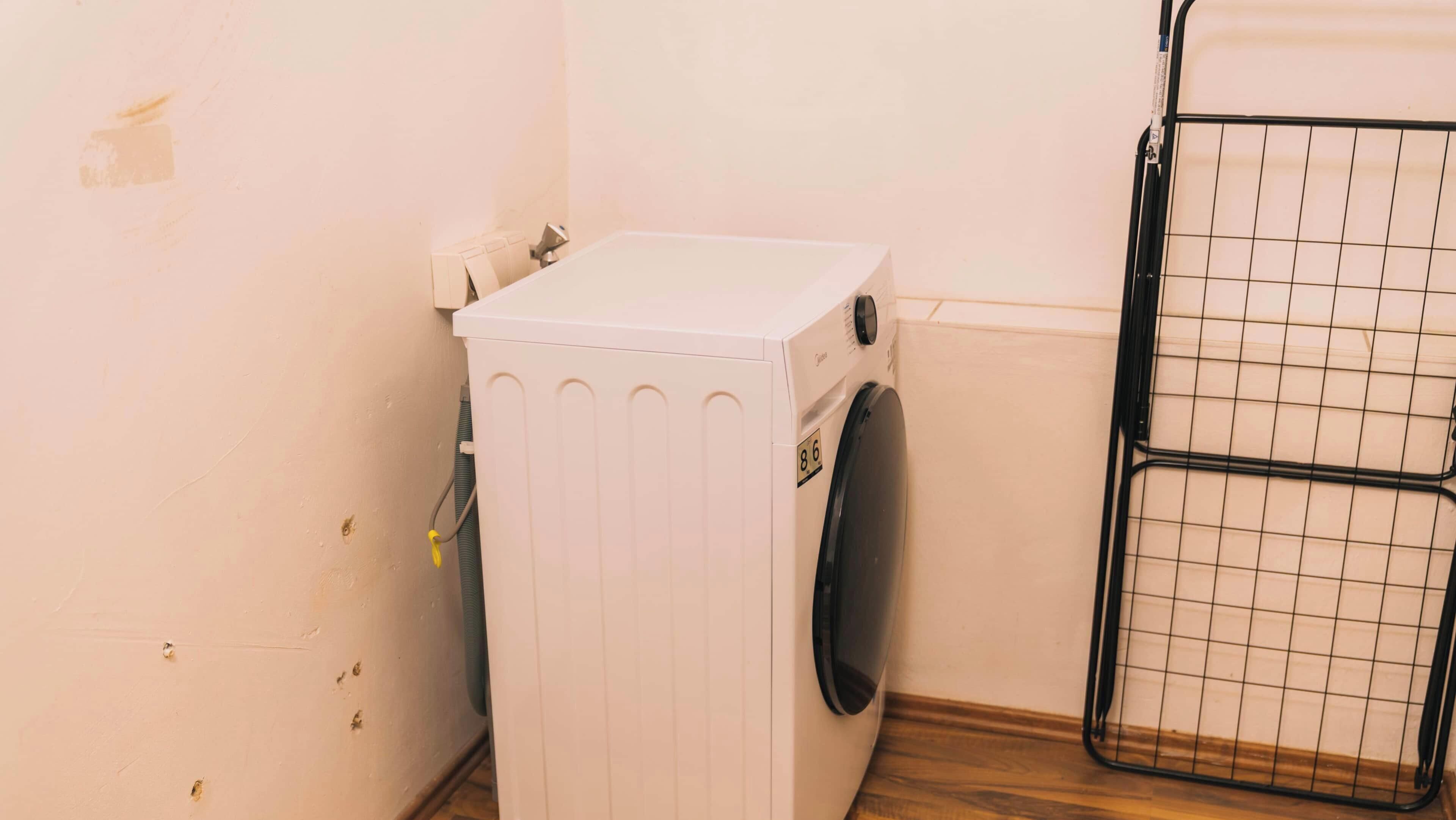 A compact laundry area with a washing machine and a drying rack.