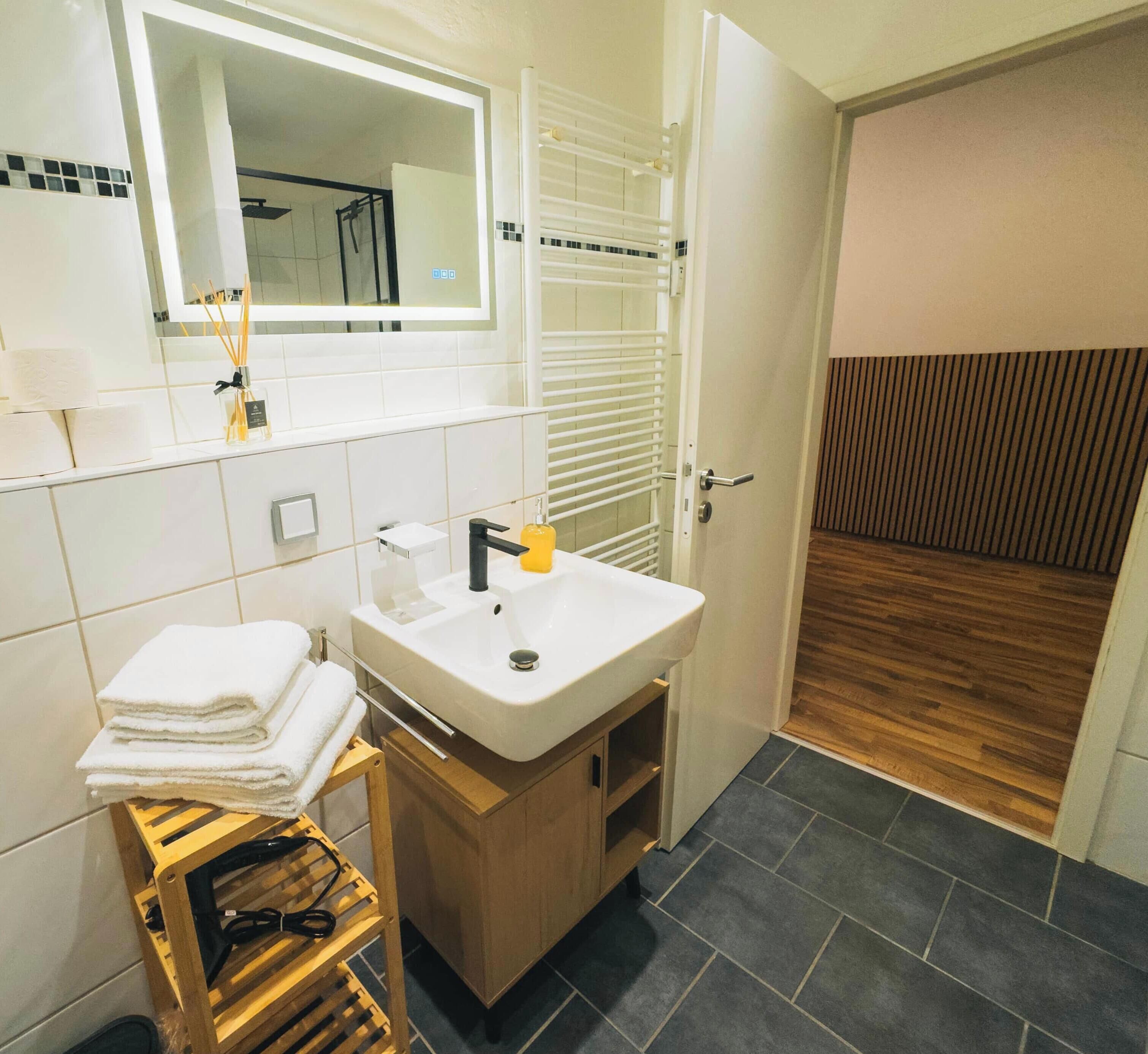 Un bagno moderno con lavandino, specchio e porta asciugamani bianchi.