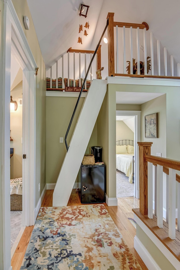 A staircase with a wooden handrail and white balusters, leading to a second-floor landing with a sign reading "Lake Place". - The Owl Cottage (Aiken)