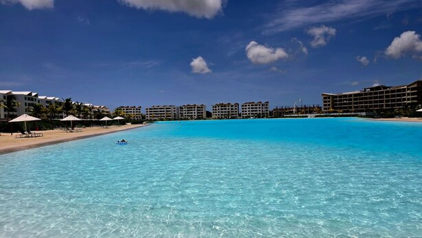 A clear blue pool with lounge chairs and umbrellas, surrounded by hotel buildings. - Oasis Turquesa Punta Cana Crystal Lagoon (Punta Cana)