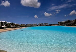 A clear blue pool with lounge chairs and umbrellas, surrounded by hotel buildings. - Oasis Turquesa Punta Cana Crystal Lagoon (Punta Cana)