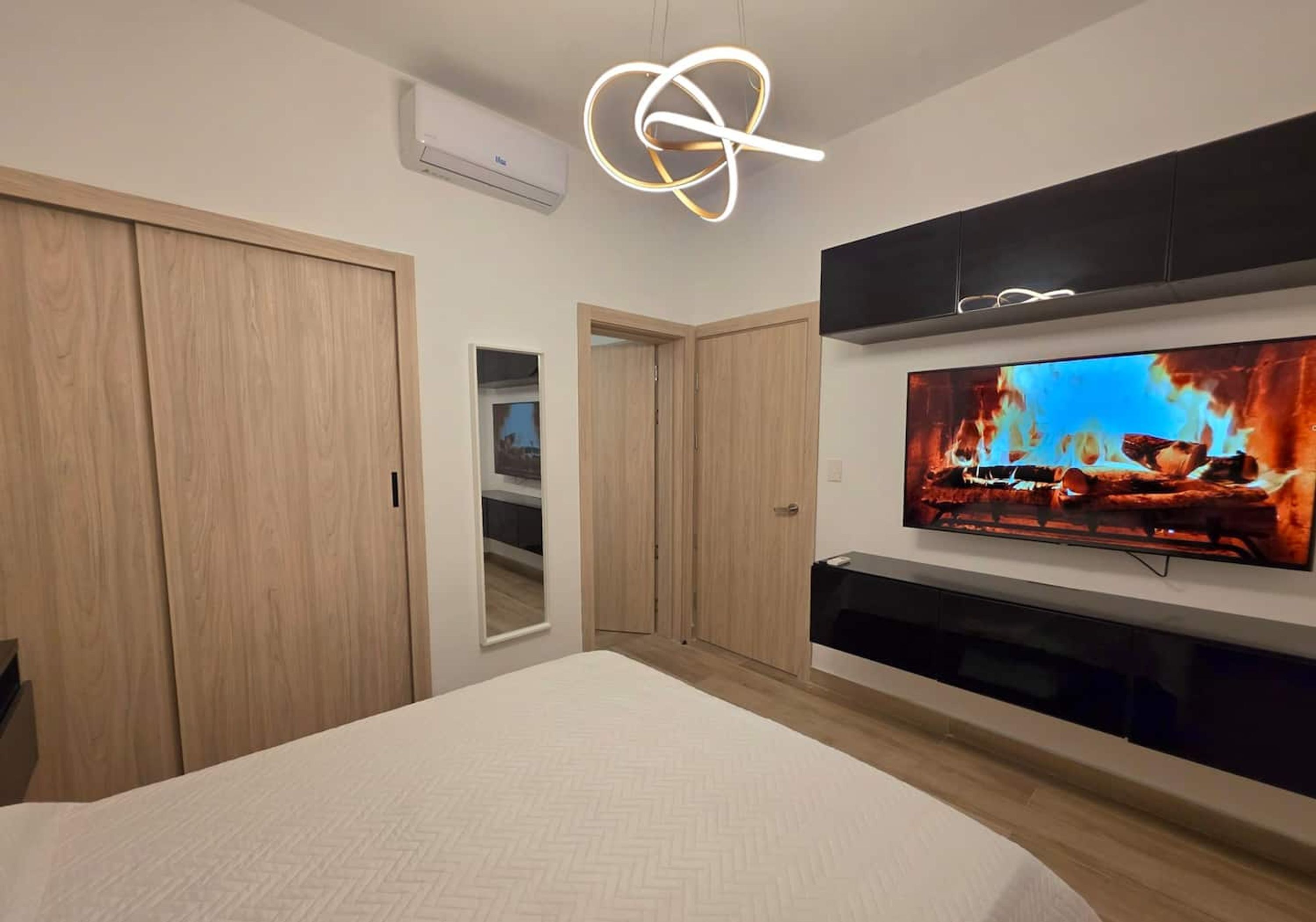 Un dormitorio con una cama, un televisor montado en la pared y un armario.