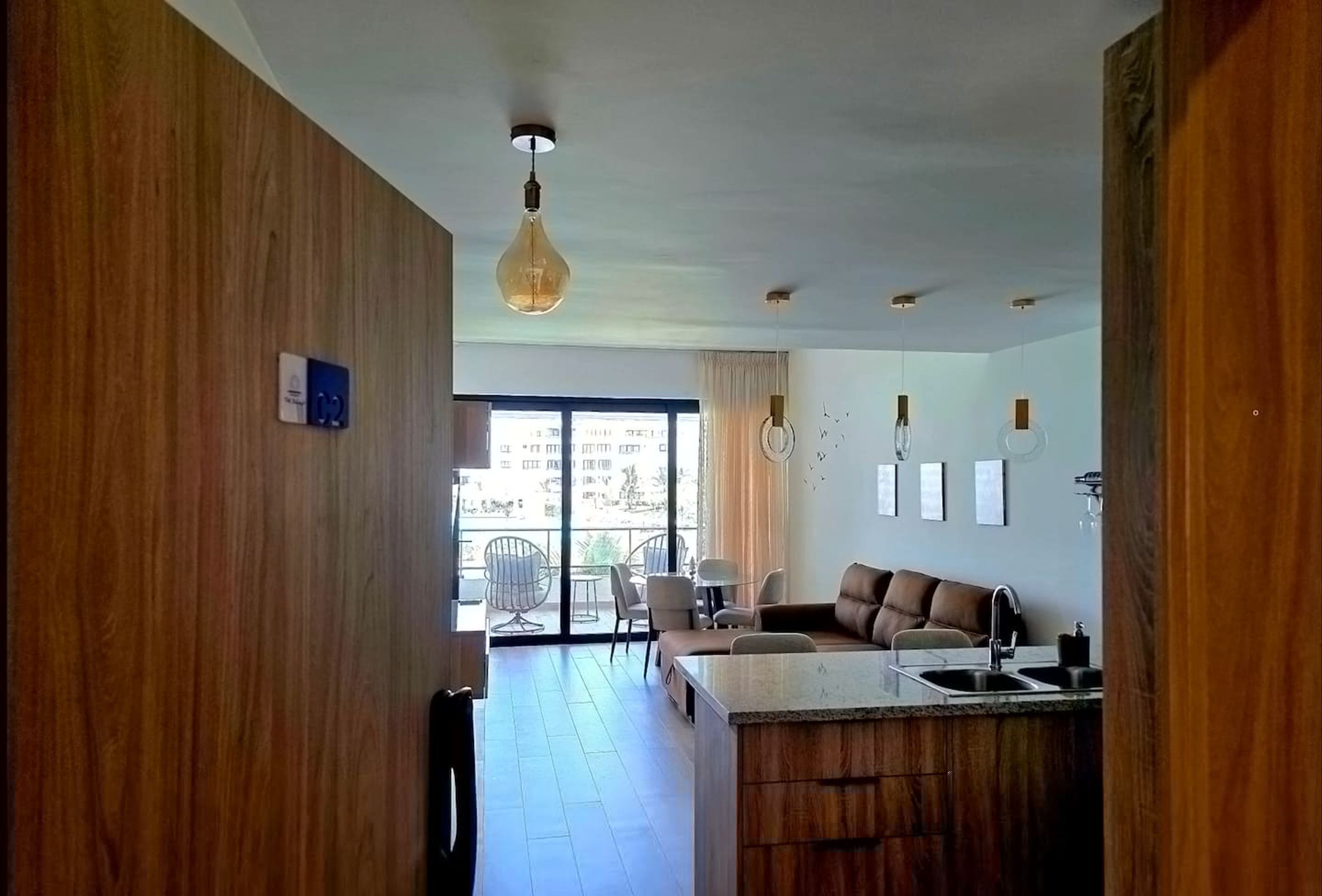 A modern kitchen with a wooden island, a dining area with chairs, and a large window with curtains.