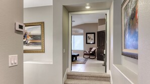 A hallway with a carpeted staircase leading to a room with a bed, a chair, and a door. - Corparate executive and Luxury family 4-bedroom house in lovely Henderson (Henderson)