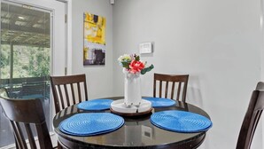 Ein Esstisch mit vier blauen Platzsets, einer Blumenvase und zwei Holzsesseln.