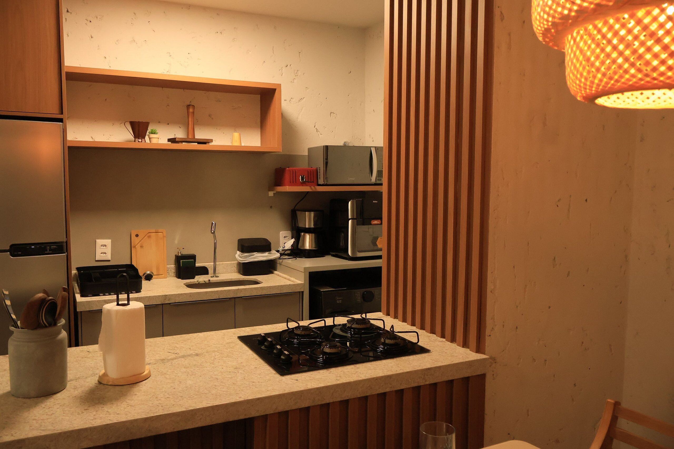 Una cocina compacta con estufa a gas, microondas y cafetera.