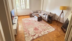 A living room with a sofa, coffee table, rug, and a lamp. - Cozy stay in prime central of Cairo, Green & Nile View. (Cairo Governorate)