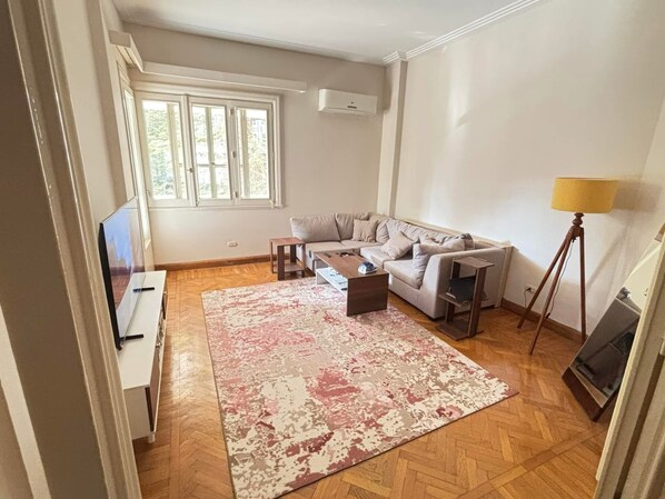 A living room with a sofa, coffee table, rug, and a lamp.