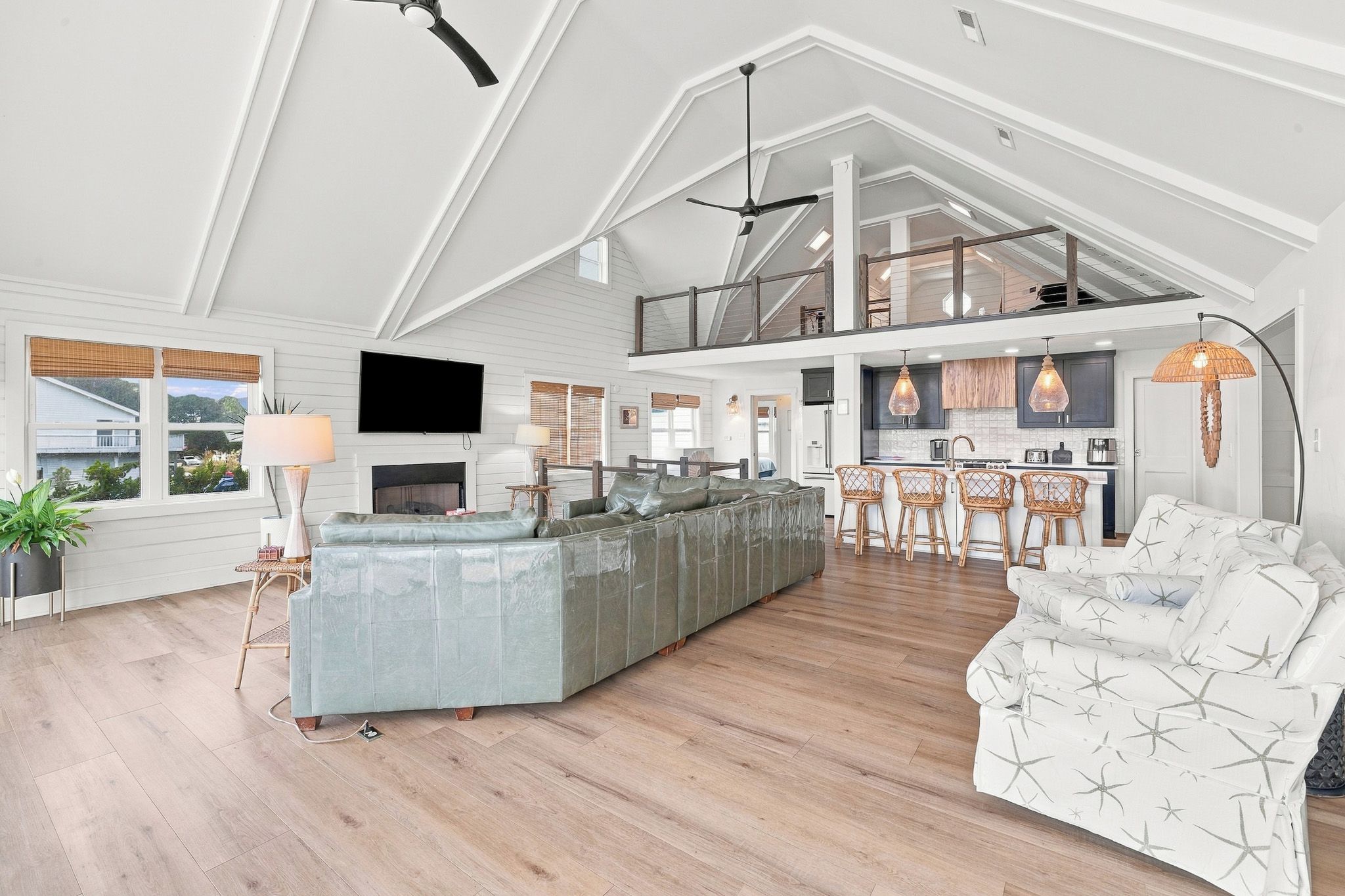 A spacious living area with a high ceiling, a central island, a sofa, and a dining area with chairs.
