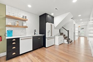 A modern kitchen with white cabinets, a black refrigerator, and a wooden floor. - Waterfront Bay Views, Private Pool, 6 Bedroom, Pet-Friendly! Sleeps14 (Virginia Beach)
