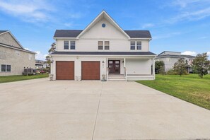 A two-story residential house with a front porch, two garage doors, and a clear sky. - Waterfront Bay Views, Private Pool, 6 Bedroom, Pet-Friendly! Sleeps14 (Virginia Beach)