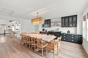 A spacious kitchen with a large wooden dining table, dark cabinets, and a hanging light fixture. - Waterfront Bay Views, Private Pool, 6 Bedroom, Pet-Friendly! Sleeps14 (Virginia Beach)