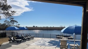 A covered patio with lounge chairs and umbrellas overlooking a body of water. - Waterfront Bay Views, Private Pool, 6 Bedroom, Pet-Friendly! Sleeps14 (Virginia Beach)
