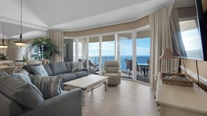 Un'ampia zona giorno con un divano grande, un tavolino da caffè e una poltrona. È presente un balcone con vista sull'oceano.