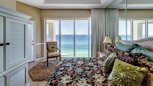 Una camera da letto con un letto grande, una sedia, un armadio e vista sull'oceano.