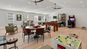 Una sala de estar amplia con mesa de billar, zona de juegos y una mesa de juegos para niños.