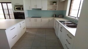 Una cocina moderna con gabinetes blancos, salpicadero de azulejos y pileta de acero inoxidable.