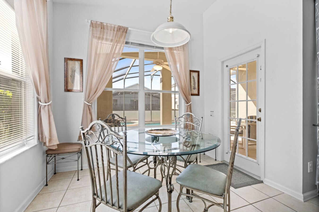A dining area with a glass table, metal chairs, and a ceiling light.