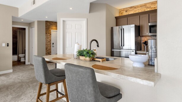 A modern kitchen with a marble countertop, stainless steel appliances, and a stone backsplash. - Upscale 2BR/2BA Condo with Great Views, Heated Pool & Balcony (Fountain Hills)