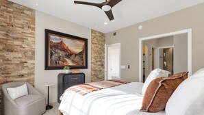 A bedroom with a bed, a chair, a painting, and a ceiling fan. - Upscale 2BR/2BA Condo with Great Views, Heated Pool & Balcony (Fountain Hills)