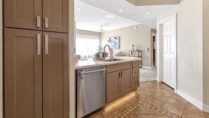 A kitchen with brown cabinets, a stainless steel dishwasher, and a tiled floor. - Upscale 2BR/2BA Condo with Great Views, Heated Pool & Balcony (Fountain Hills)