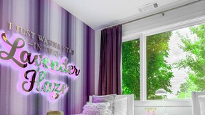 Une chambre à coucher comprenant un lit, une table de chevet, une fenêtre avec des rideaux et un mur orné d’un élément décoratif.