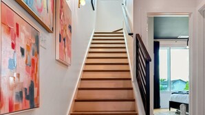 Un escalier avec des marches en bois et une rampe noire, menant à une pièce comprenant un lit et une fenêtre.