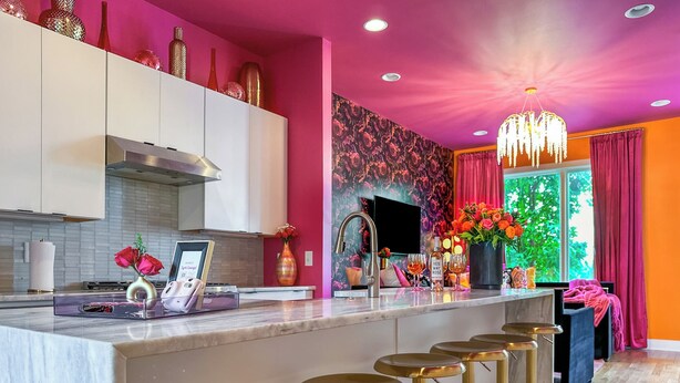 Une cuisine moderne dotée d’un îlot central, de tabourets de bar et d’un mur décoratif.