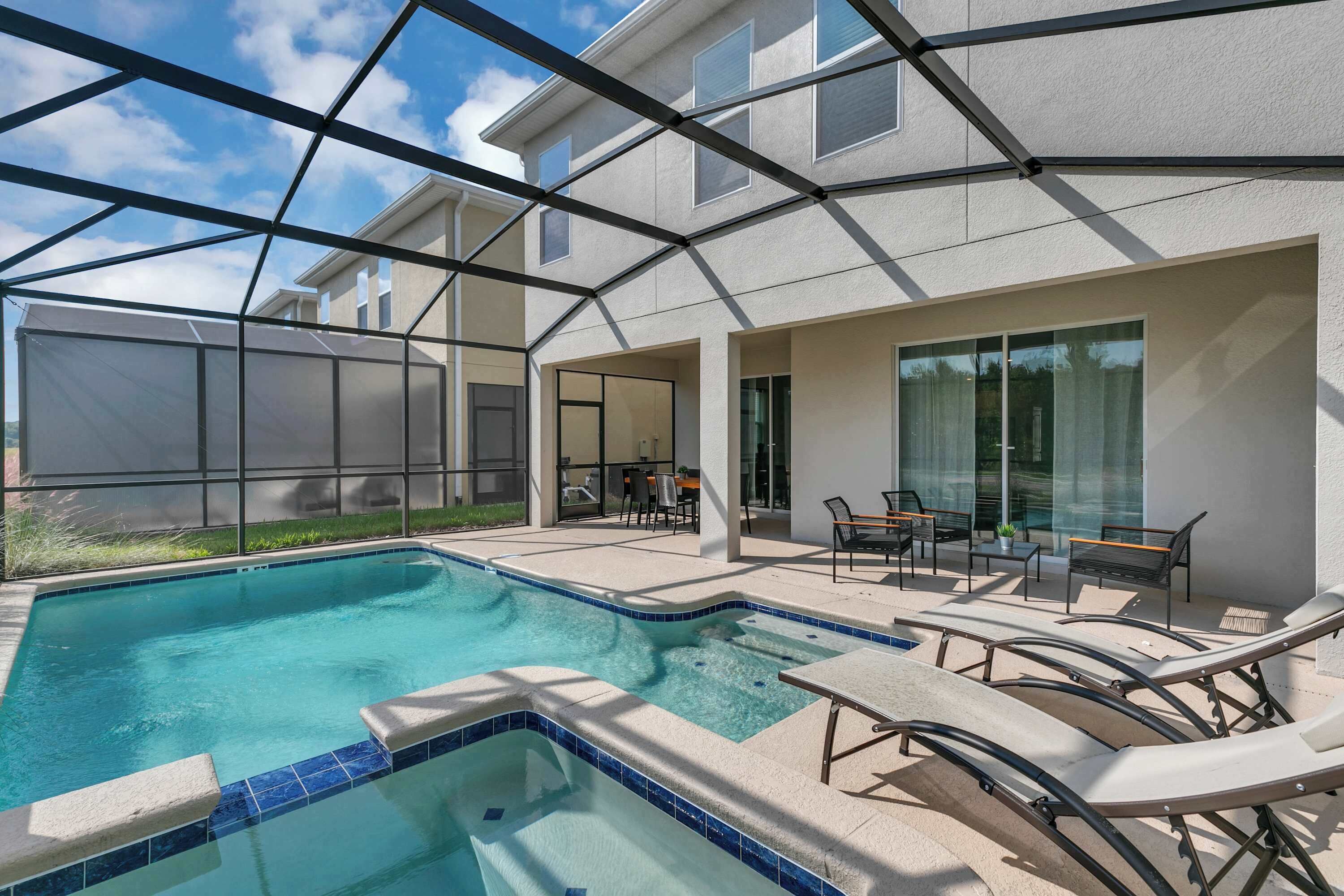 A swimming pool with lounge chairs and a covered patio area.
