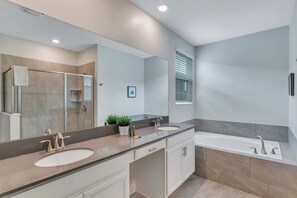 A modern bathroom with a large mirror, two sinks, a bathtub, and a potted plant. - Classy 6BR Home With Private Pool (Kissimmee)
