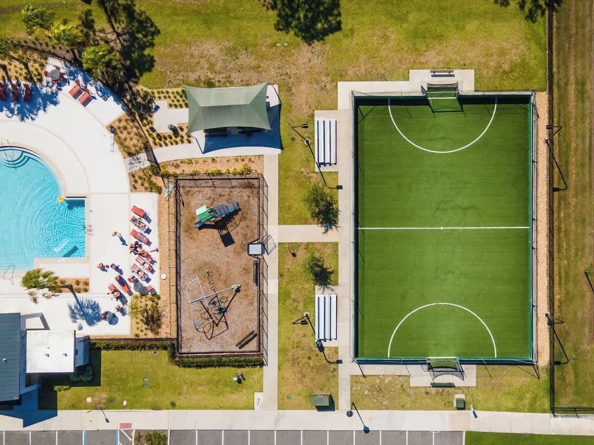 Vue aérienne d’une propriété dotée d’une piscine, d’un court de tennis et d’un patio couvert.