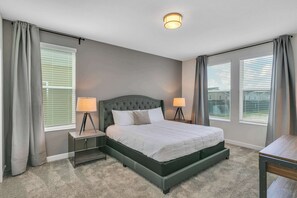 A bedroom with a large bed, two bedside lamps, and a nightstand. - Classy 6BR Home With Private Pool (Kissimmee)