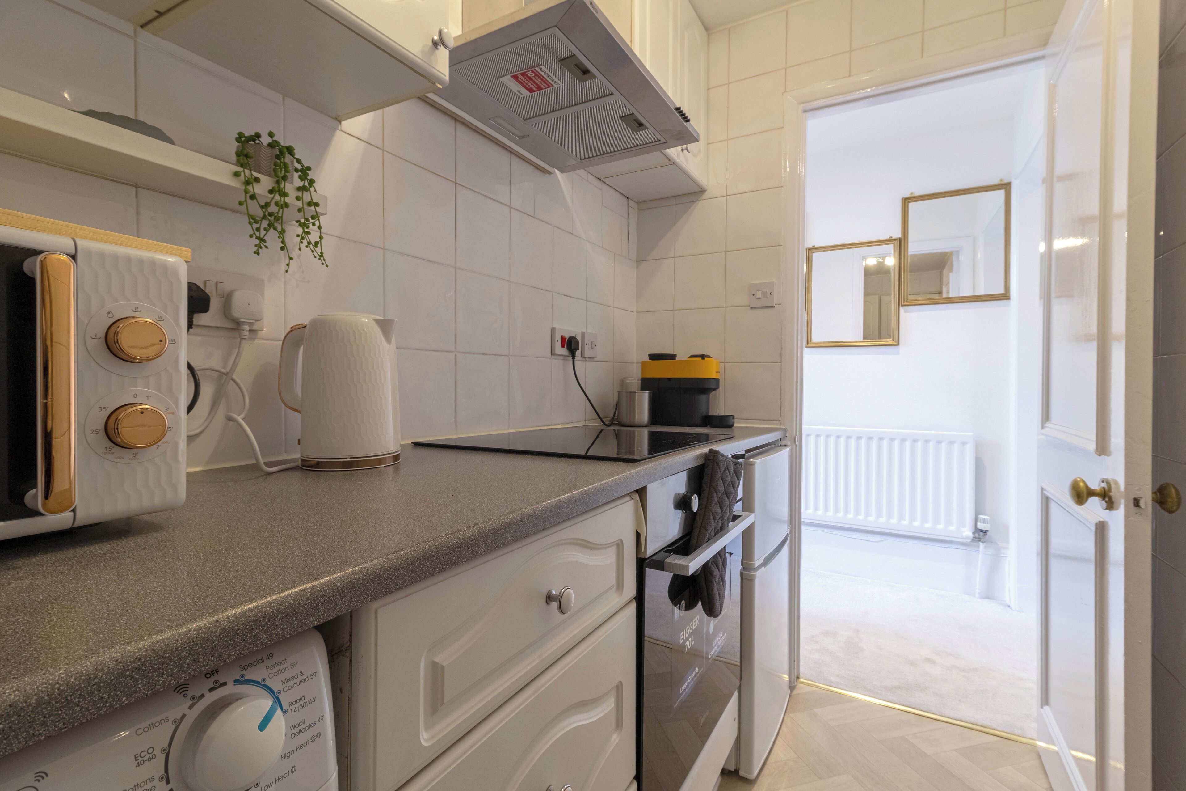 Eine moderne Küche mit weißen Schränken, einem Backofen, einer Kaffeemaschine und einem Wasserkocher.