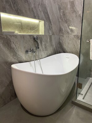 A modern bathroom with a freestanding bathtub, a glass shower enclosure, and marble walls. - Fahari Suites By WW (Dar es Salaam)
