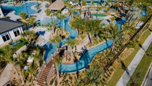 Ovenfra ses et resort med flere swimmingpools, palmer og velplejede omgivelser.