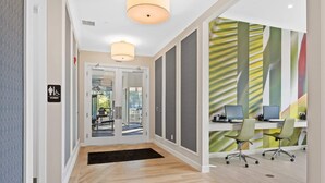 A modern office space with a reception area, a woman’s restroom sign, and a desk with computers. - Classy 6BR Home With Private Pool (Kissimmee)